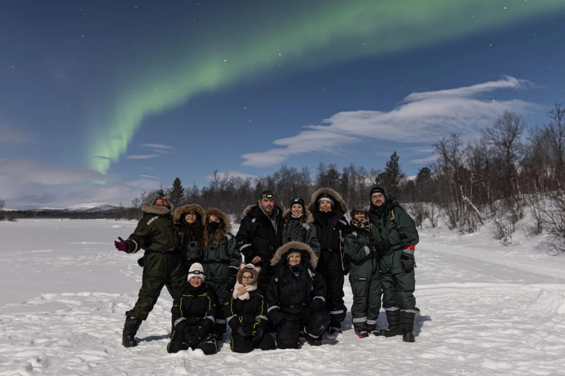 Our guest group on a frozen lake under the aurora on a bright full moon night outside Kiruna