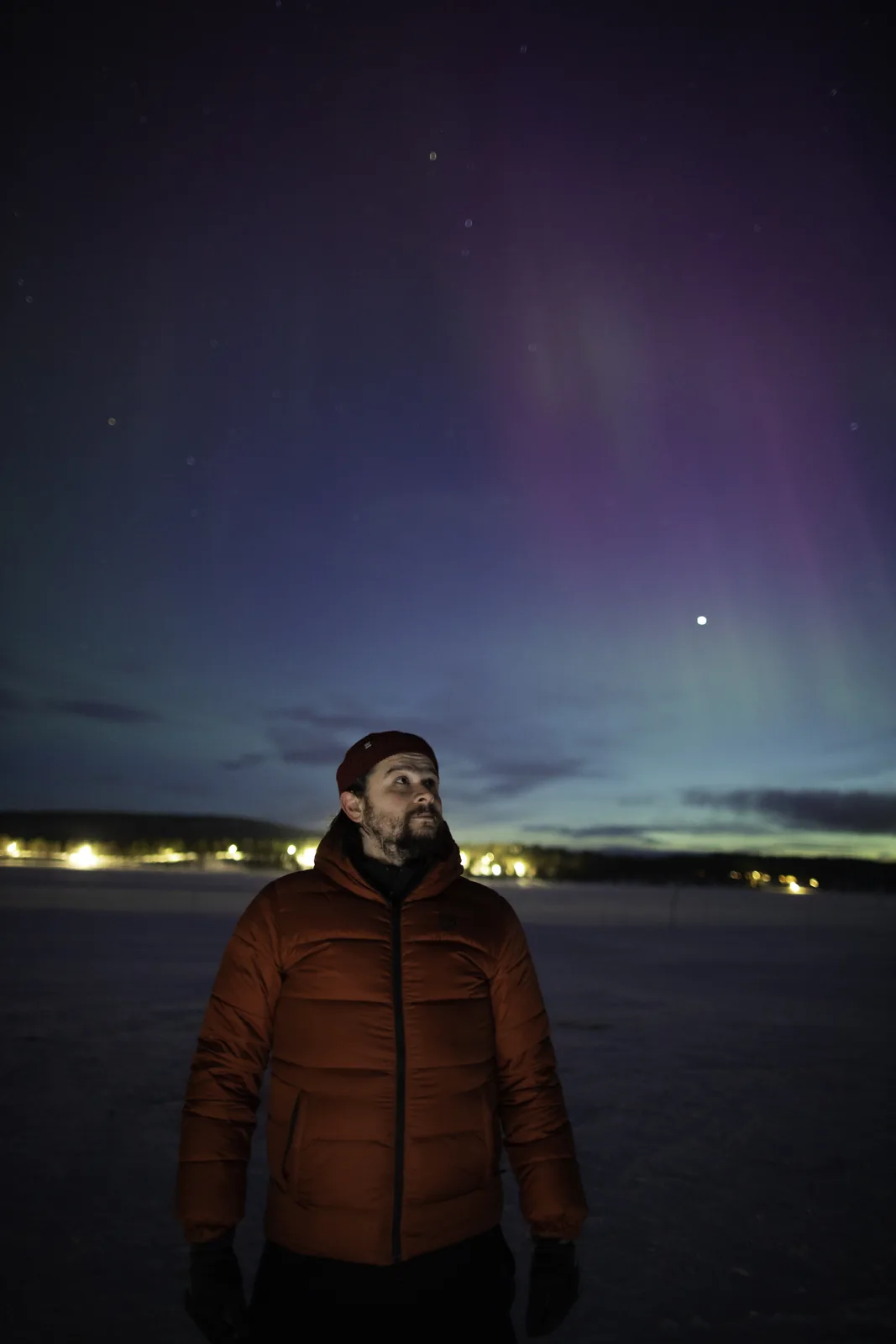 One of our guides in an orange jacket looking up at the aurora near Kiruna