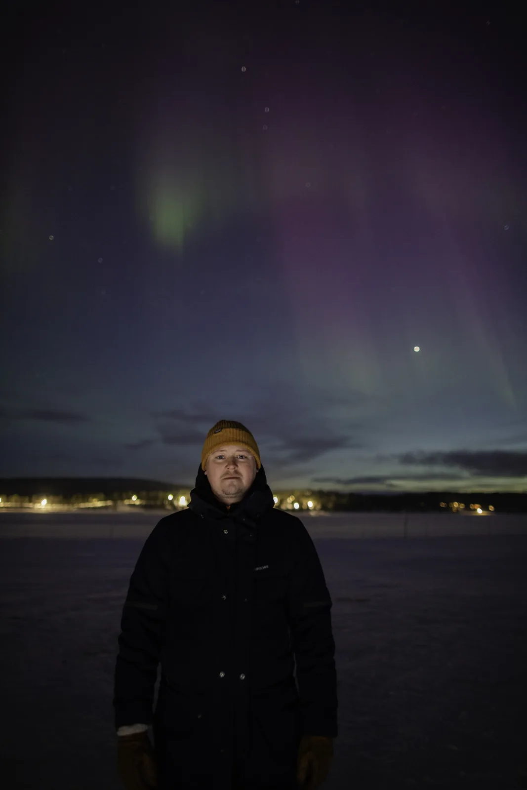 One of our guides standing under the aurora on a frozen lake outside Kiruna