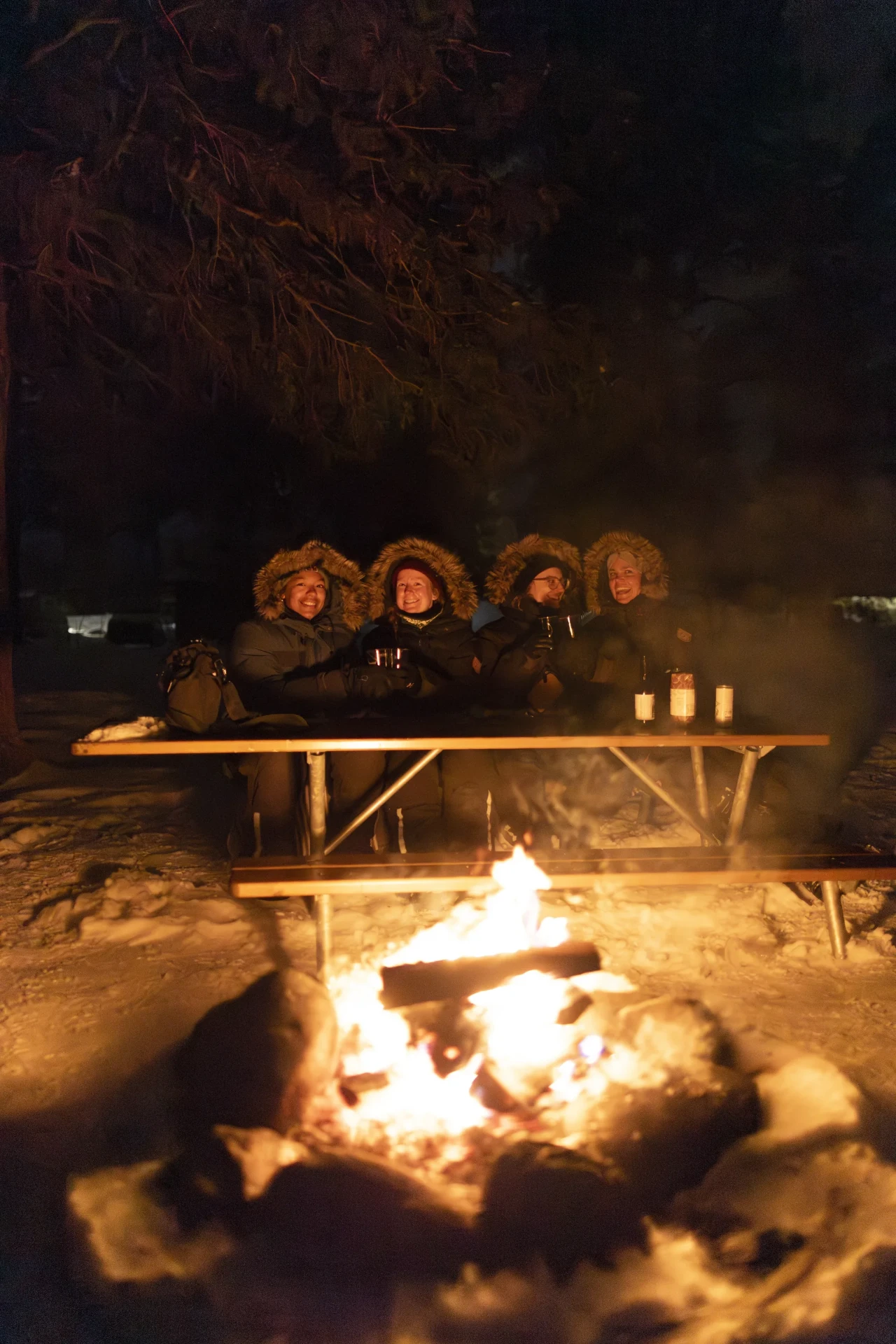 Guests eating together around an open fire in the evening outside Kiruna