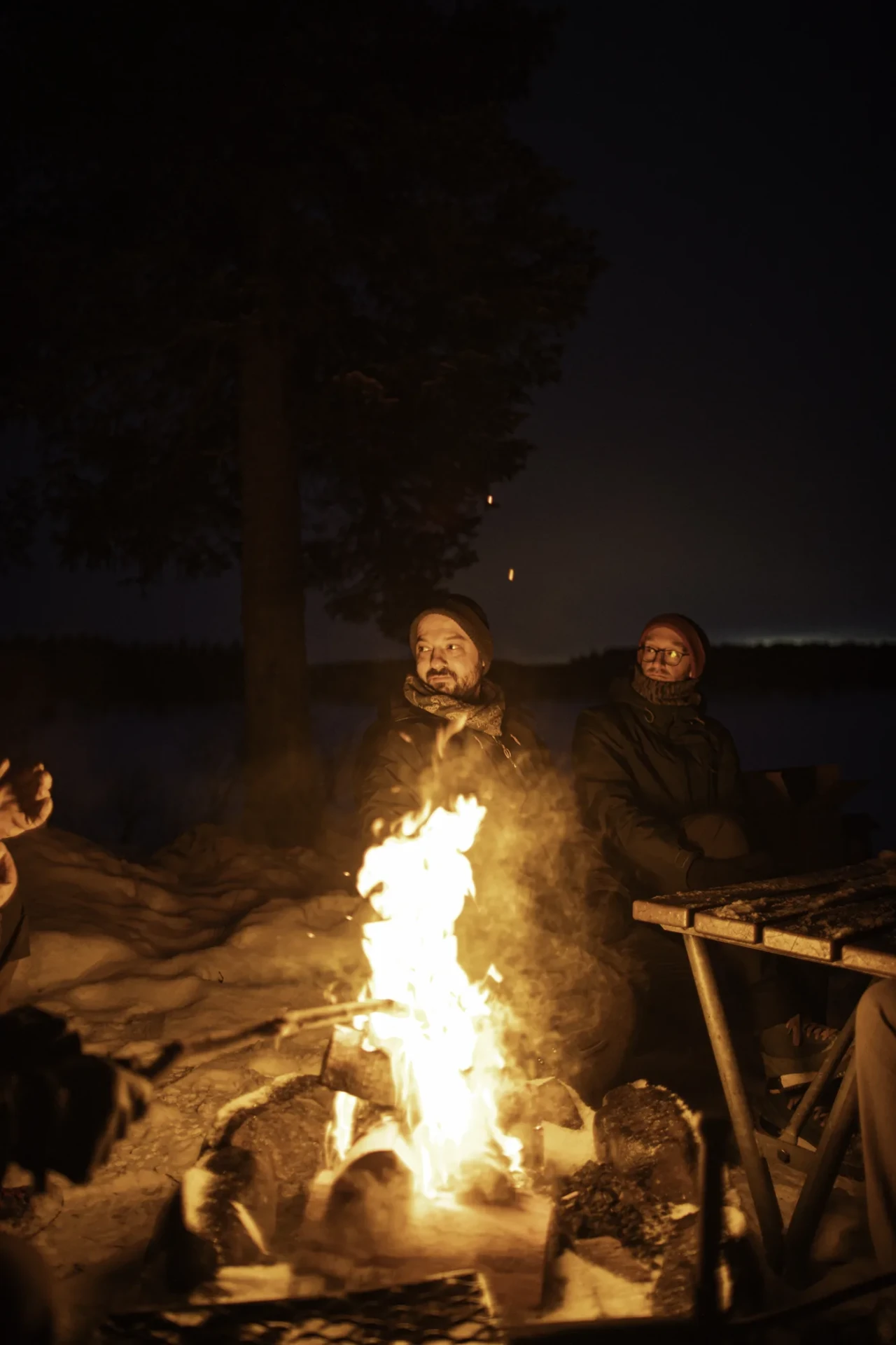 Guests gathered around the fire with hot drinks after dark