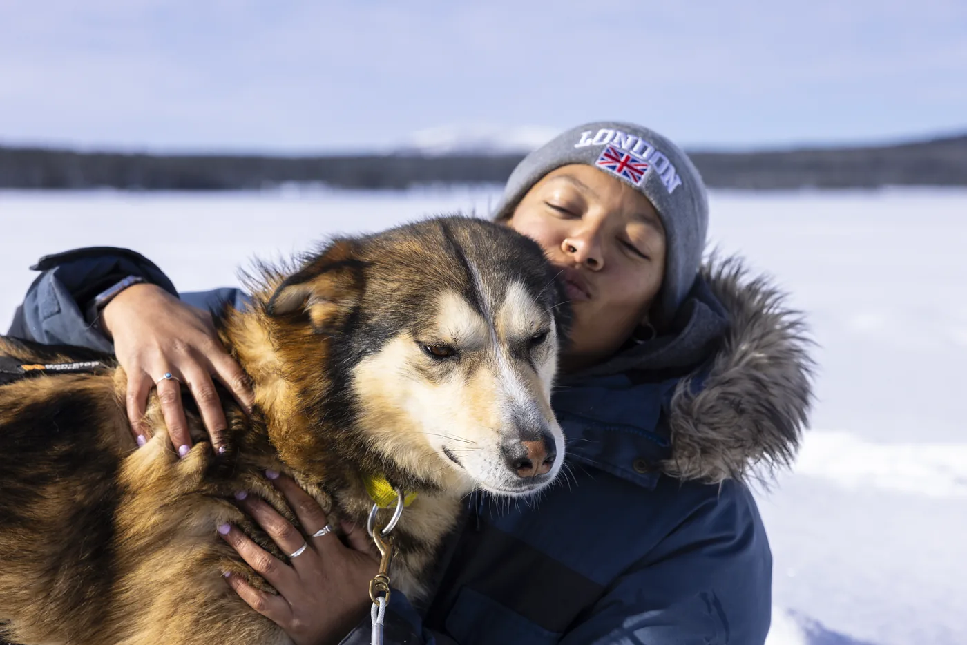 Guest hugging a sled dog on a frozen lake