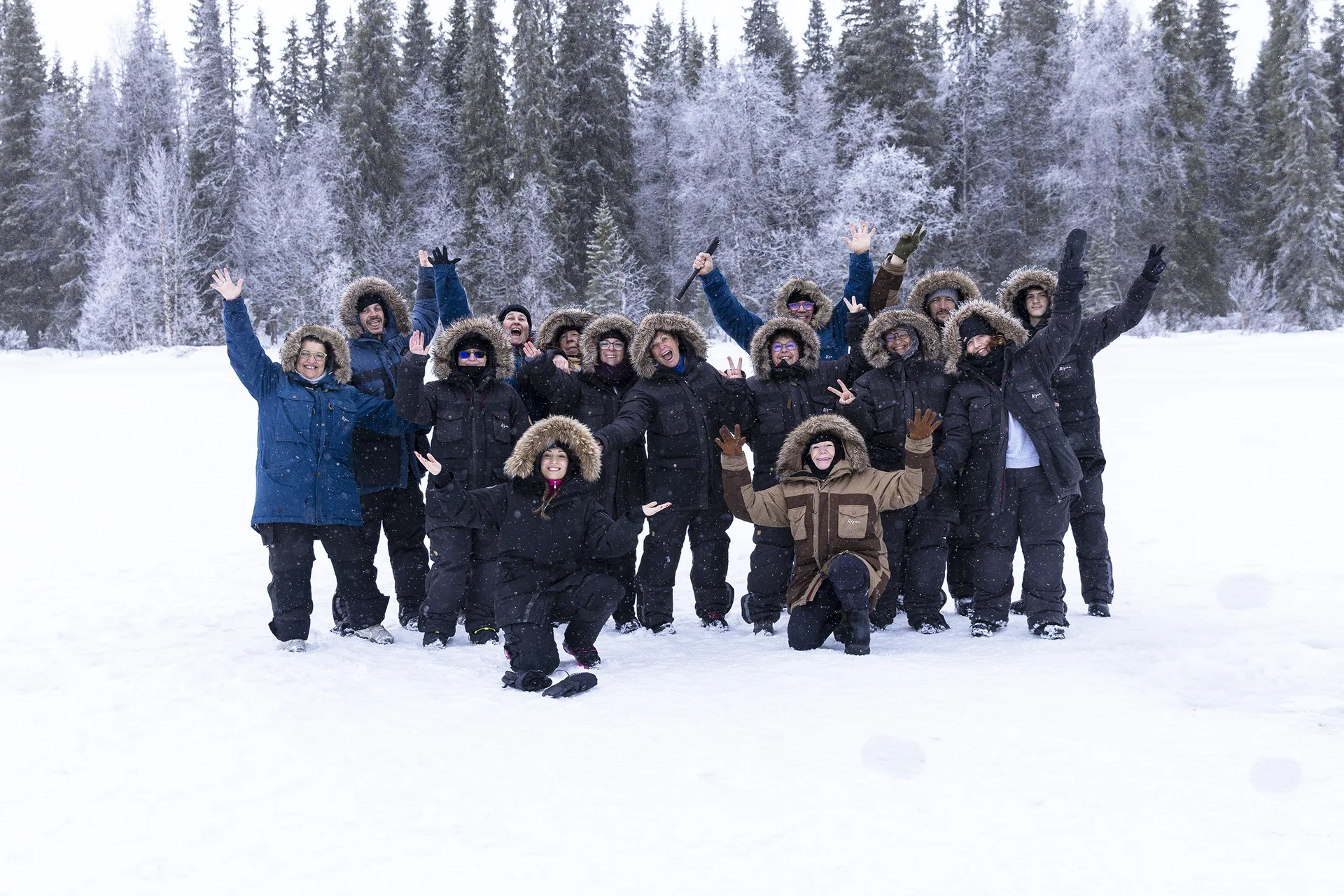 Our guests cheering with arms in the air in a snowy forest outside Kiruna