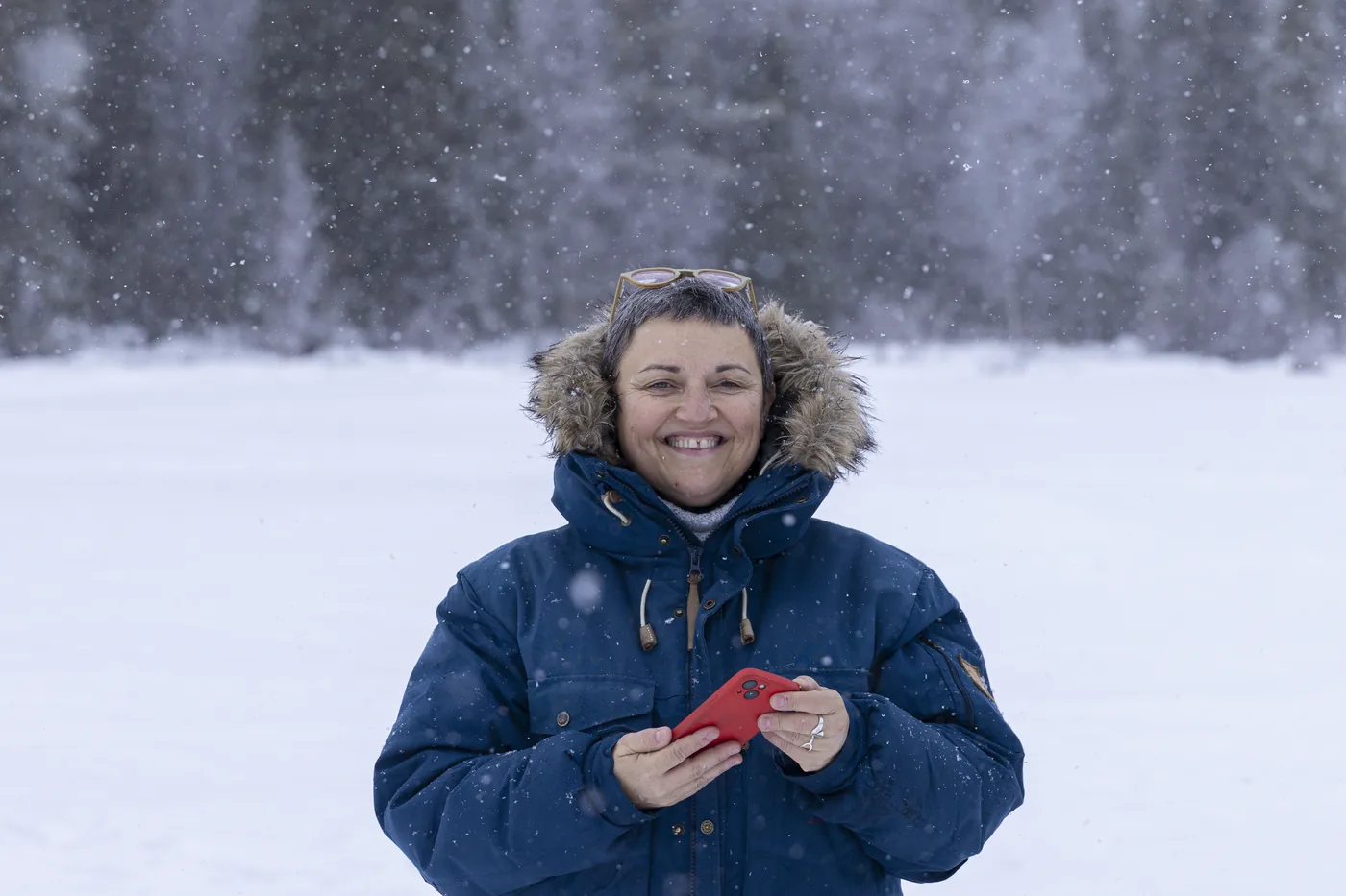Guest smiling in heavy falling snow, dressed in the winter clothing set we provide