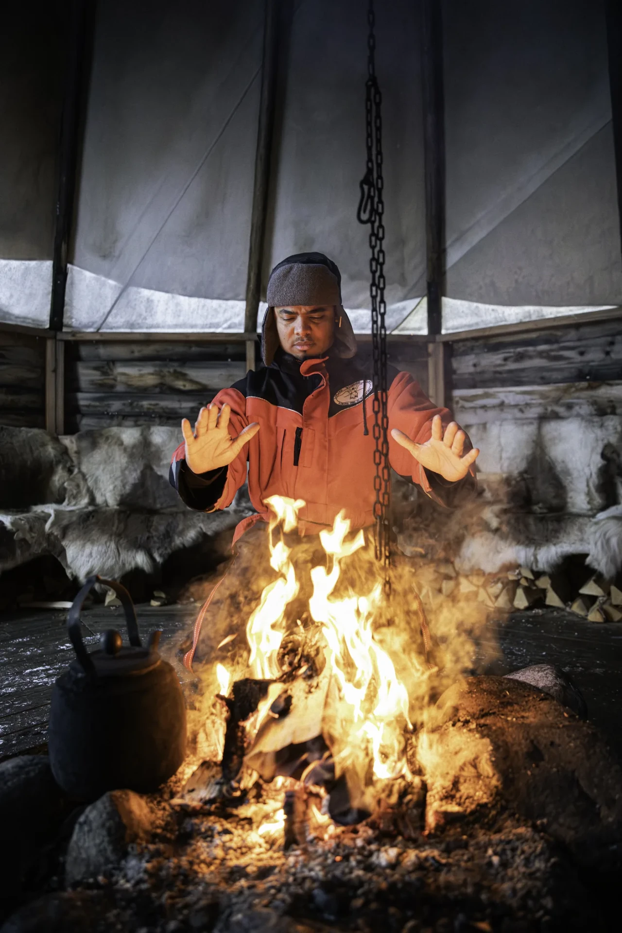 Guide warming his hands over the open fire in the lavvu where we take fika