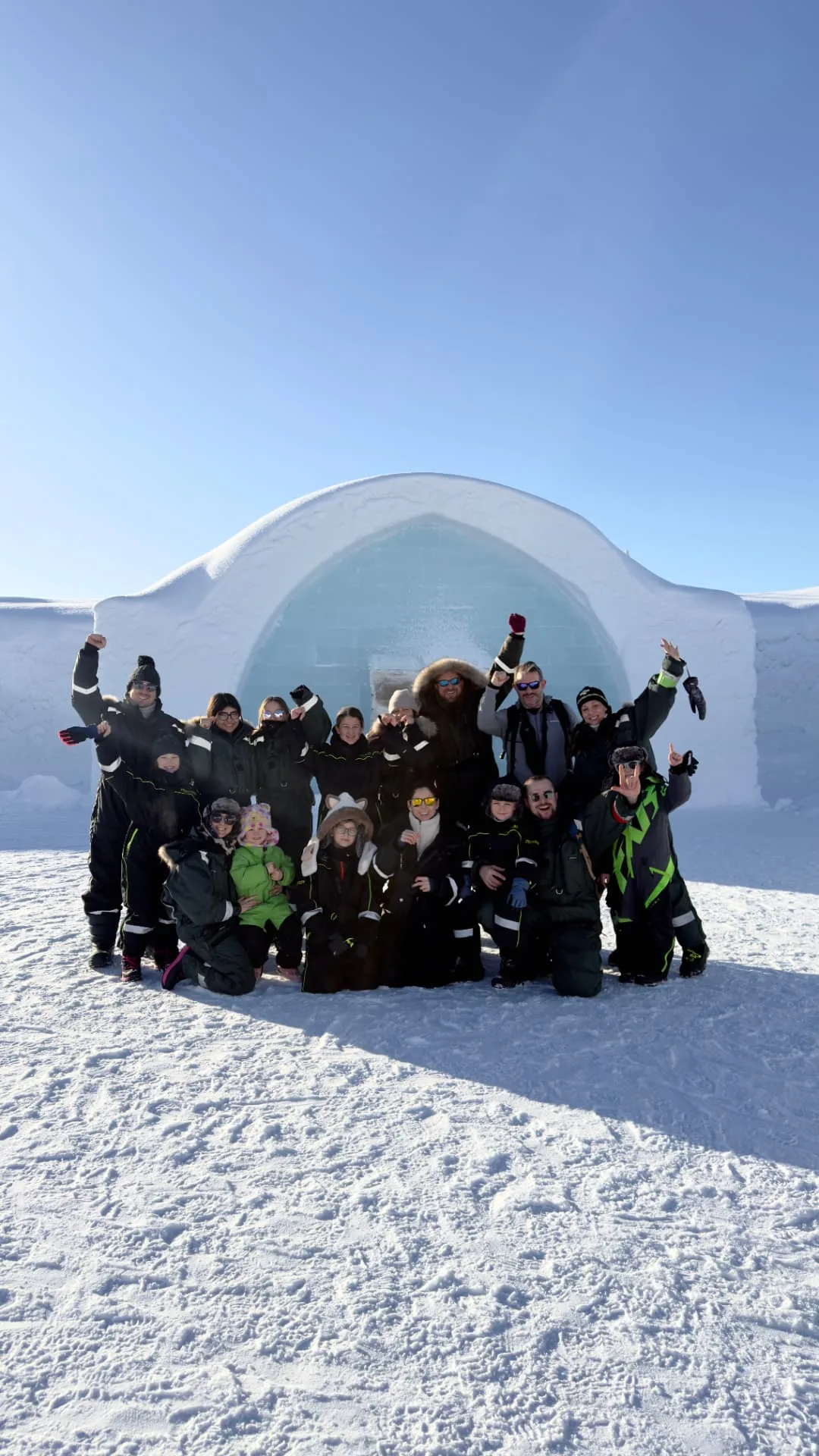 Guest group in front of the snow-covered ICEHOTEL entrance on a clear blue day