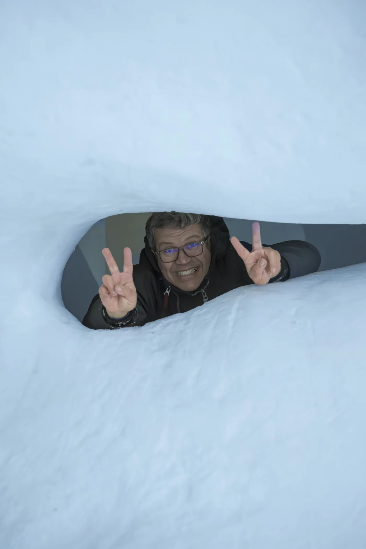 Guest smiling through an opening in the snow at the ICEHOTEL
