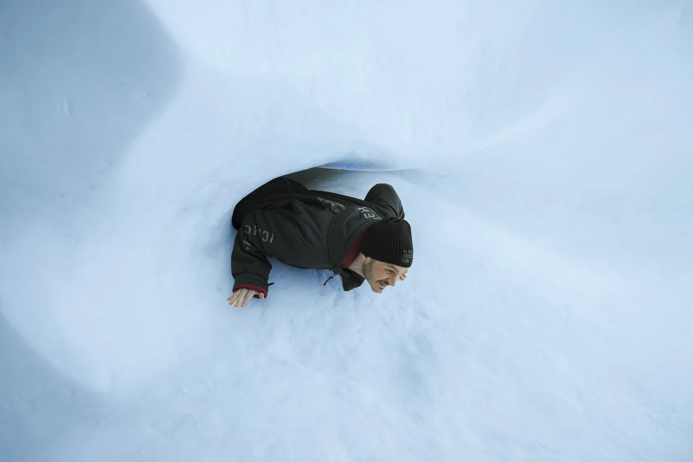 Guest crawling through a carved snow tunnel at the ICEHOTEL