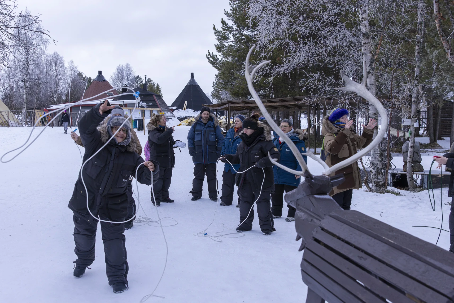 Guests practising reindeer lasso throwing at a Sámi camp near Kiruna