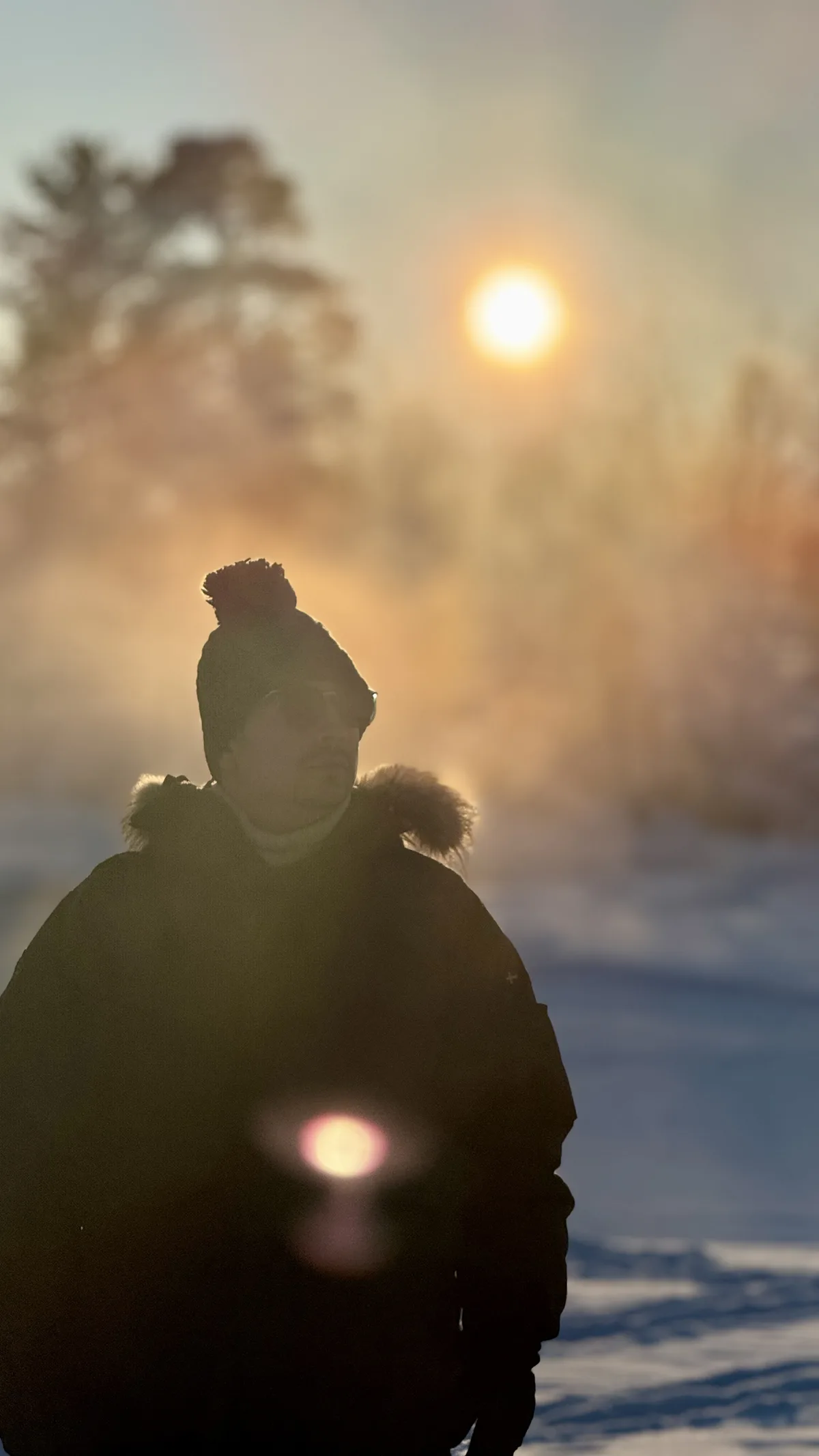 Guest standing in the low Arctic sun and ice fog outside Kiruna